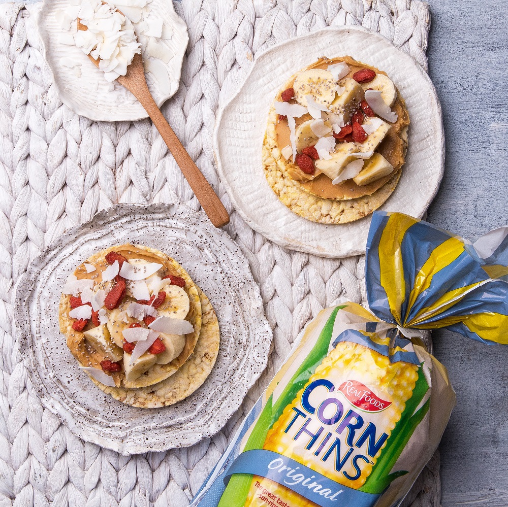 Nut Butter, banana, coconut flakes & goji berries on Corn Thins slices for breakfast