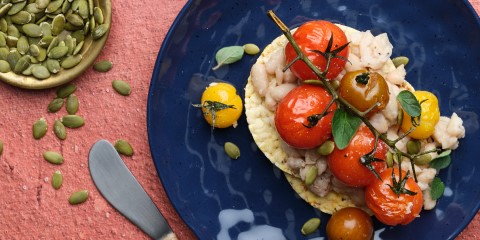 Smashed white bean, roast cherry tomato, pepita, oregano on Corn Thins slices