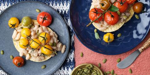 Smashed white bean, roast cherry tomato, pepita, oregano on Corn Thins slices