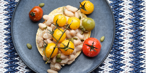 Smashed white bean, roast cherry tomato, pepita, oregano on Corn Thins slices