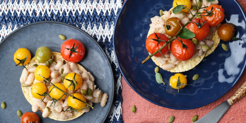 Smashed white bean, roast cherry tomato, pepita, oregano on Corn Thins slices